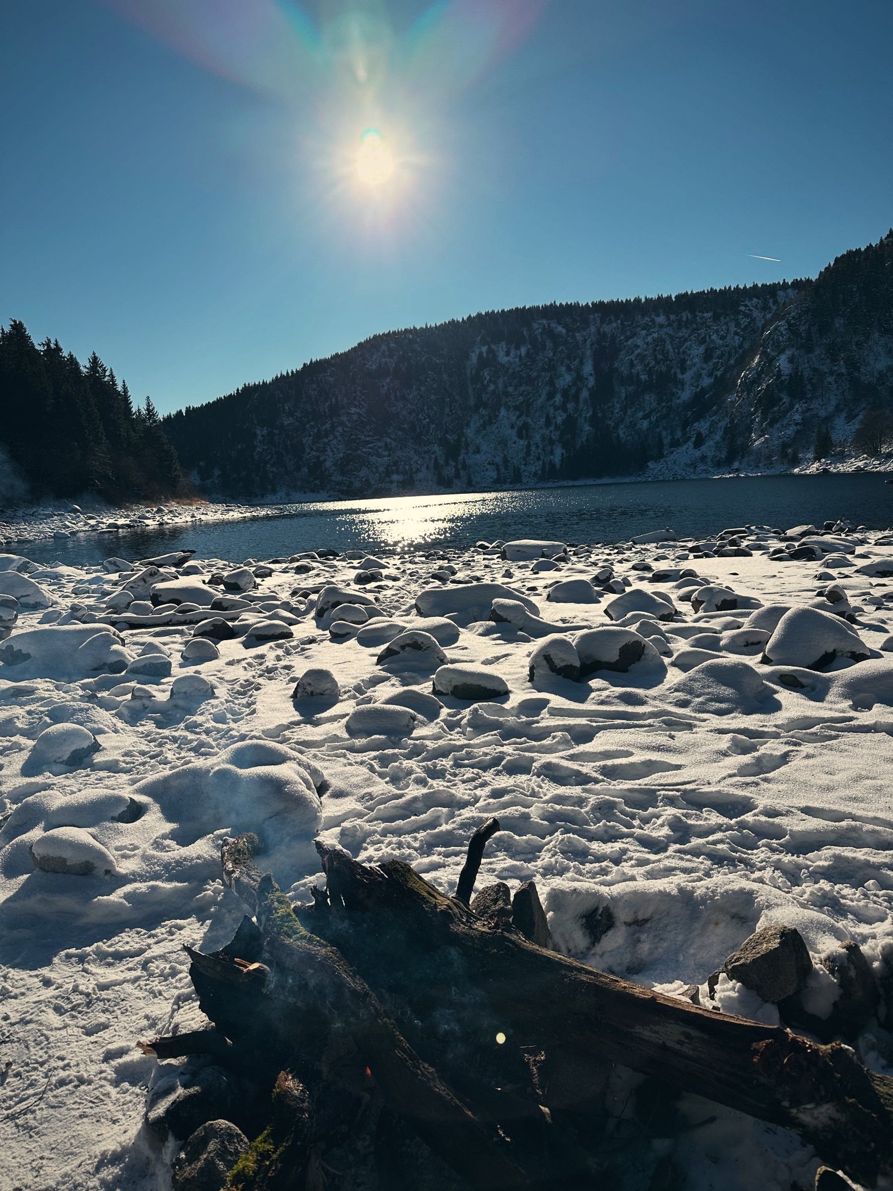Verschneites Ufer des Lac Blanc mit Sonne über dem Kamm