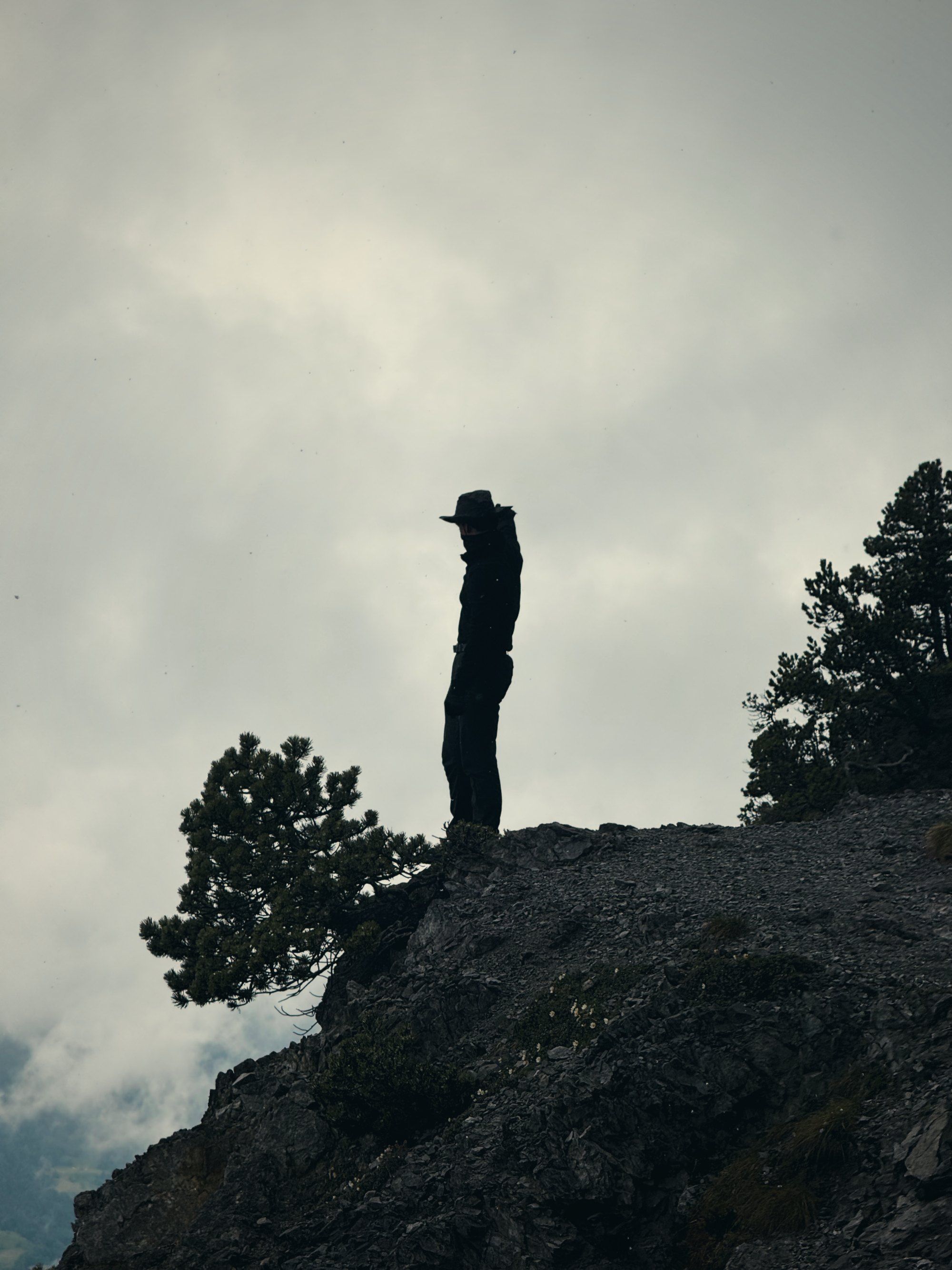 Silhouette eines Wanderers auf einem Felsvorsprung im Nebel