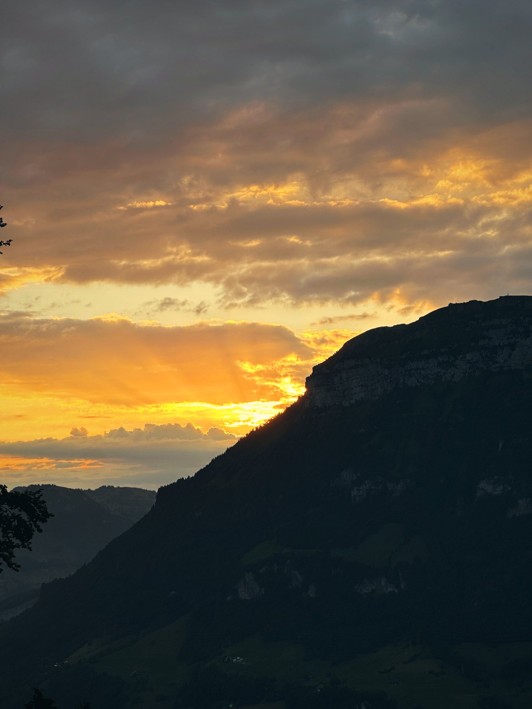 Sonnenaufgang mit orangem Himmel über einem Berg am Urnersee