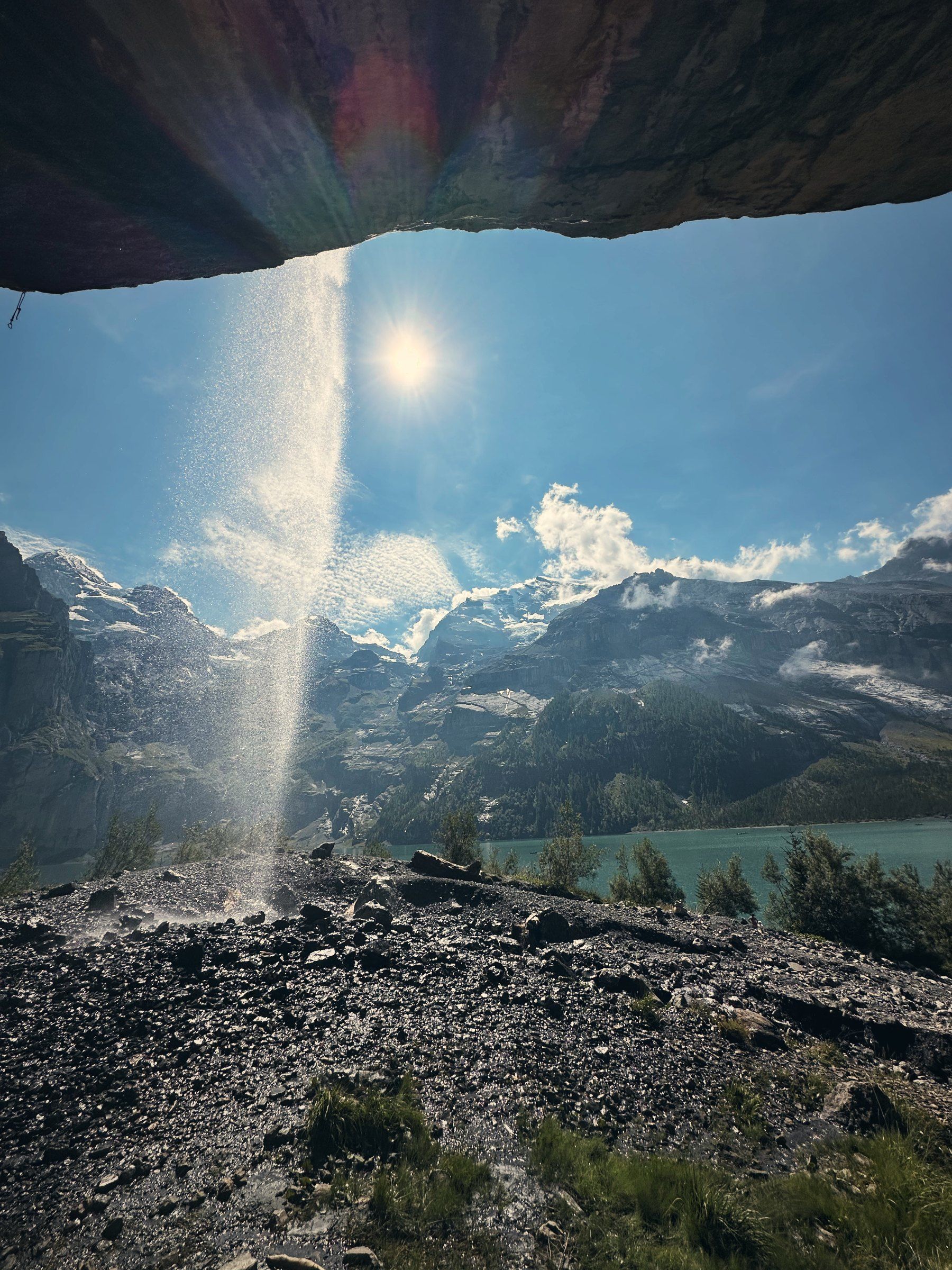 Wasserfall von unter einem Felsüberhang mit Gegenlicht