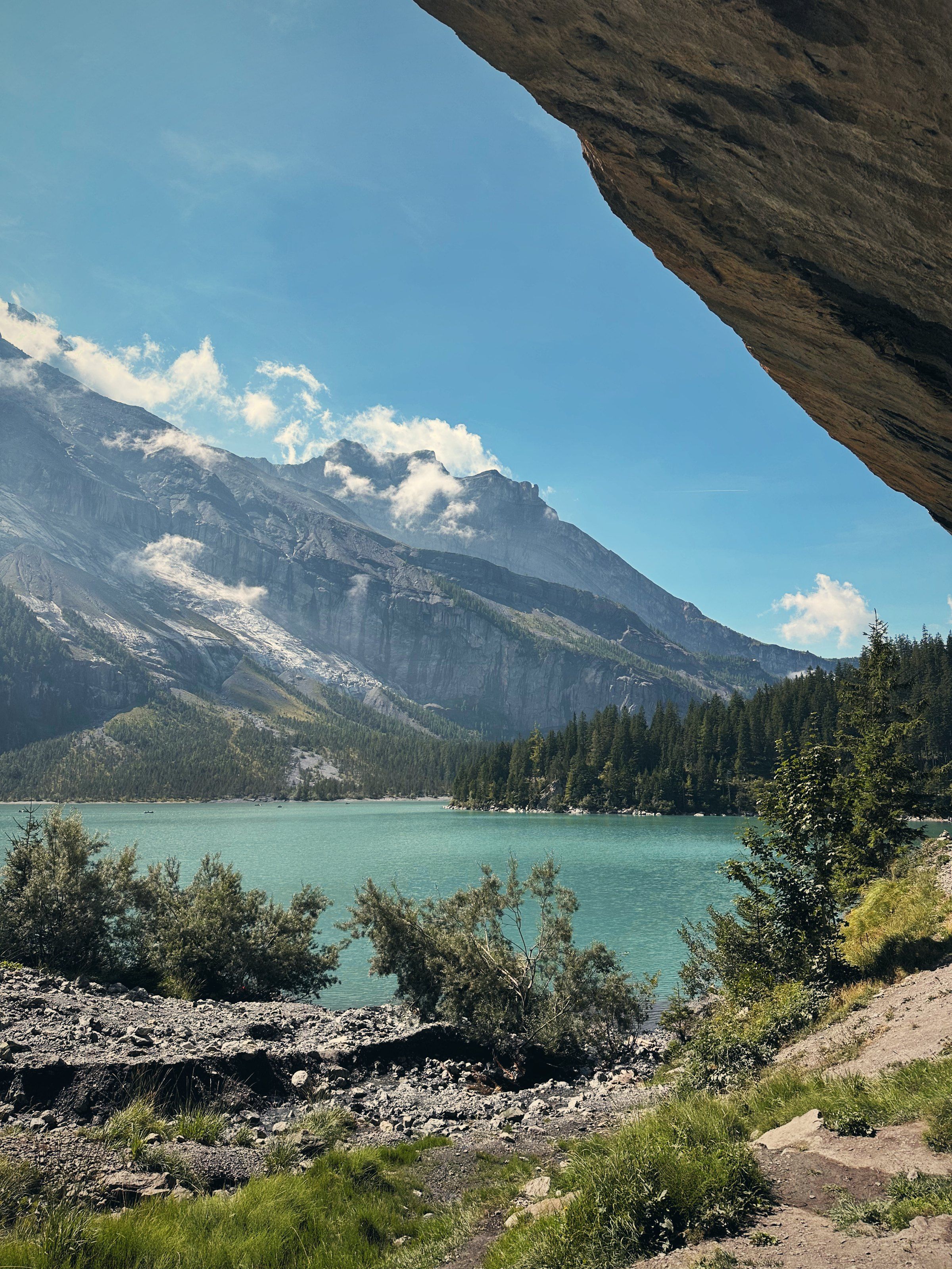 Turquoise Lake Oeschinen seen from under a rock overhang