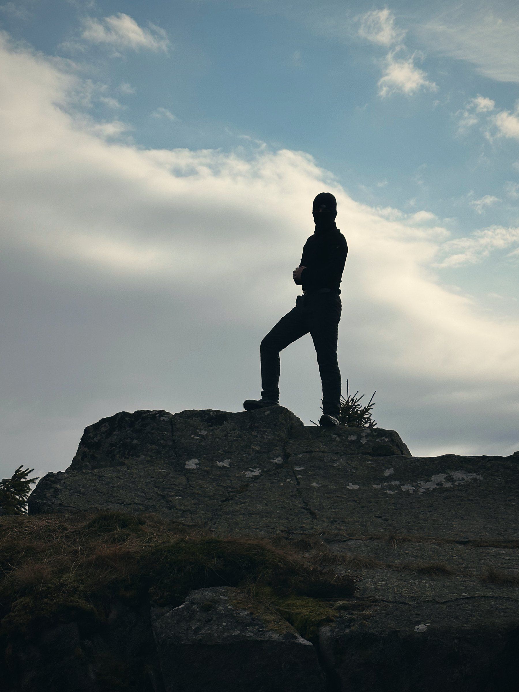 Silhouette von Tea mit Sturmhaube auf einem Felsen vor Wolken