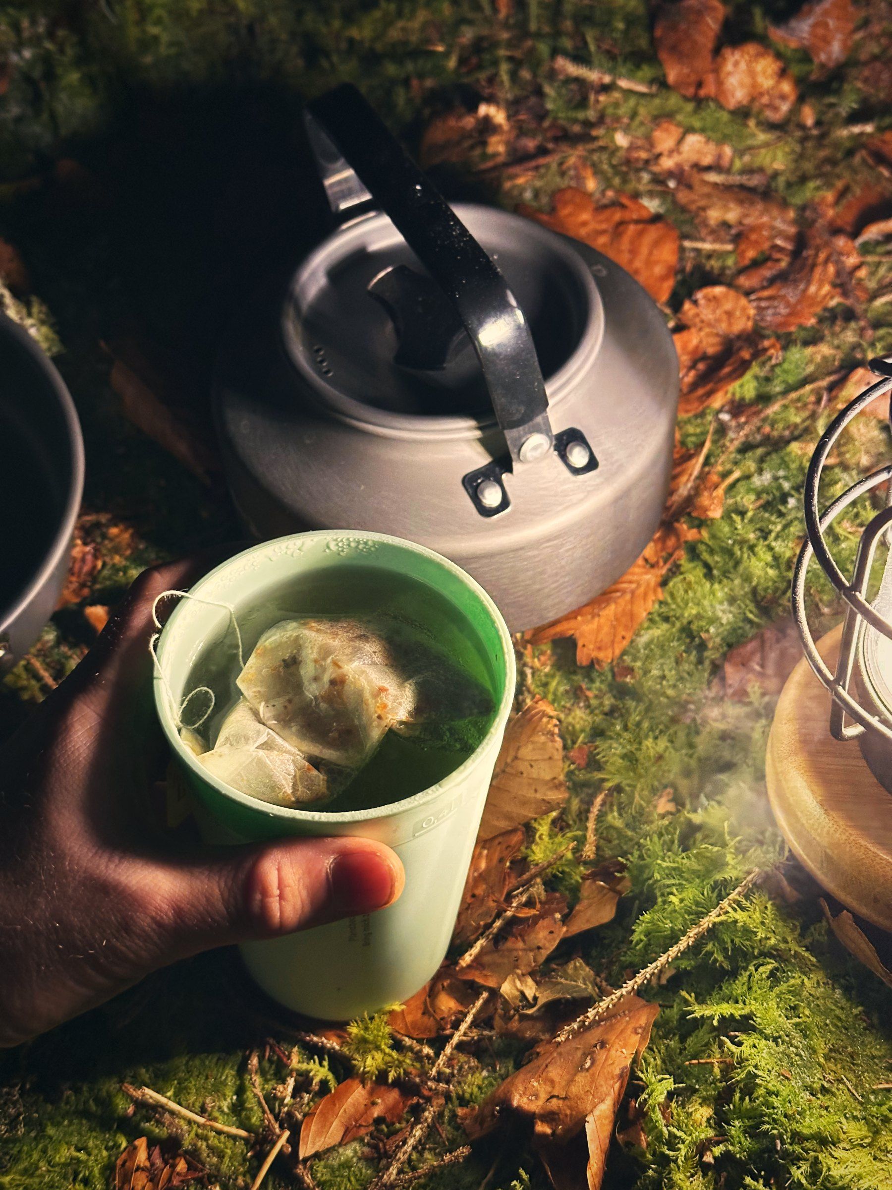 Heiße Tasse Tee neben einem Kessel und einer Laterne